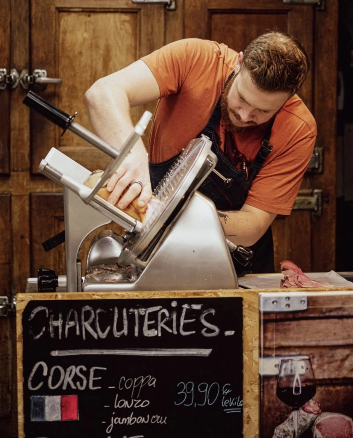 une image d'un homme entrain de trancher de la charcuterie avec une machine.